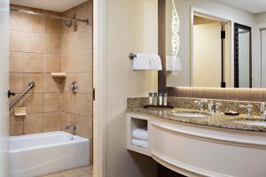 y baño con lavabo, bañera y espejo. en Gaylord Texan Resort and Convention Center en Grapevine