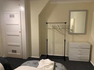 een slaapkamer met een bed, een ladekast en een spiegel bij Contractor & Family Friendly House Romford in Havering atte Bower