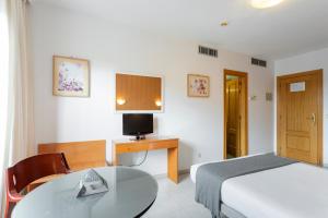 a hotel room with a bed and a table and a television at Alda Ciudad de Toro in Toro
