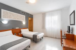 um quarto de hotel com duas camas e uma televisão em Hotel Alda Ciudad de Toro em Toro