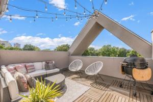 a patio with a couch and chairs on a balcony at Chic City Park Home - Rooftop Deck - Skyline Views in Denver