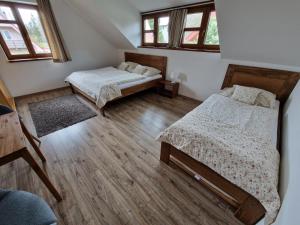 two beds in a room with wooden floors and windows at Chata Marta in Boží Dar
