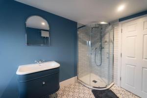 a blue bathroom with a shower and a sink at 3 The Steyne - Stunning 5 Storey Georgian house with cinema room in Worthing