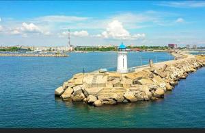 a lighthouse on a rocky island in the water at Apartament Gul Mona Saturn in Saturn