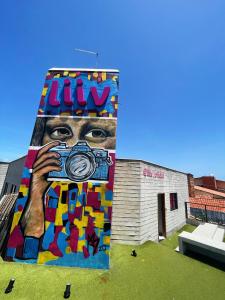 um mural na lateral de um edifício com uma câmara em Liiv Costeira - Natal Ponta Negra em Natal