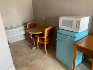 a kitchen with a table and a microwave on top of a refrigerator at Apple Valley Motel in Apple Valley