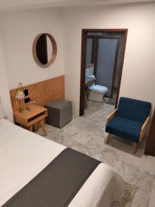 Cet appartement comprend une chambre avec un lit et une chaise bleue ainsi qu'une salle de bains. dans l'établissement CHOLULA SUITES, à Cholula