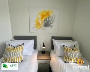 a bedroom with two beds and a picture on the wall at 2 Bedroom Apartment by Central Serviced Apartments - Perfect for Short&Long Term Stays - Family Neighbourhood - Wi-Fi - FREE Street Parking - Sleeps 4 - 2 x King Beds - Smart TV in All Rooms - Modern - Weekly-Monthly Offers - Trade Stays - Close to A90 in Dundee