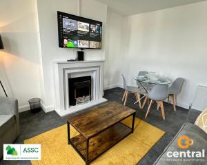 a living room with a table and a fireplace at 2 Bedroom Apartment by Central Serviced Apartments - Perfect for Short&Long Term Stays - Family Neighbourhood - Wi-Fi - FREE Street Parking - Sleeps 4 - 2 x King Beds - Smart TV in All Rooms - Modern - Weekly-Monthly Offers - Trade Stays - Close to A90 in Dundee