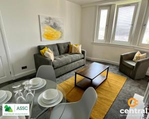 a living room with a couch and a table at 2 Bedroom Apartment by Central Serviced Apartments - Perfect for Short&Long Term Stays - Family Neighbourhood - Wi-Fi - FREE Street Parking - Sleeps 4 - 2 x King Beds - Smart TV in All Rooms - Modern - Weekly-Monthly Offers - Trade Stays - Close to A90 in Dundee