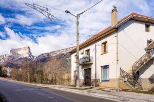 a building on the side of a street with a mountain in the background at Logement chaleureux haut de gamme dans le Trièves - WIFI - NETFLIX in Clelles