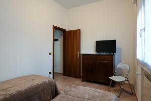 Schlafzimmer mit einem Bett, einem TV und einem Stuhl in der Unterkunft Venice Green Lagoon - 20 min da Venezia in Mestre