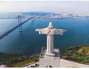 a statue of christ the redeemer in front of a bridge at Almada big flat next To Lisbon and Caparica beach in Almada