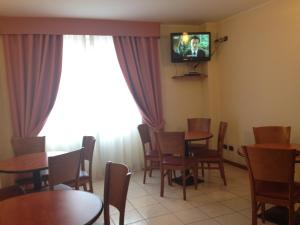 jadalnia ze stołami i krzesłami oraz telewizorem w obiekcie Hotel Belforte w mieście Varese