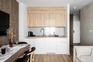 a kitchen with white cabinets and a table with chairs at Apartamenty Podhale in Zakopane