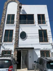 喬盧拉的住宿－CHOLULA SUITES，两辆汽车停在白色建筑前面