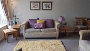 uma sala de estar com um sofá com almofadas roxas e amarelas em Cromarty Cottage Eastbourne em Pevensey