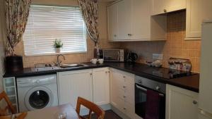 a kitchen with a sink and a washing machine at Cromarty Cottage Eastbourne in Pevensey