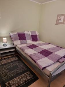 a bed with a purple and white comforter in a room at P2-Nyaraló in Magyarhertelend