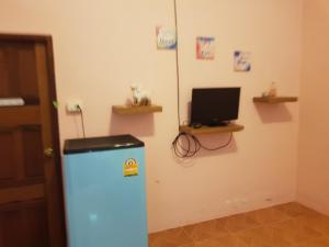 een kamer met een koelkast en een tv aan de muur bij โอคันทรี Ocountry in Khuang Nai