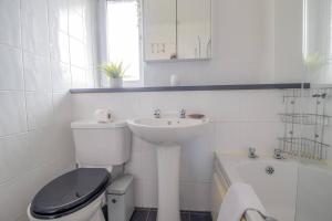 a white bathroom with a toilet and a sink at Pass the Keys Prime Paisley with Parking in Paisley