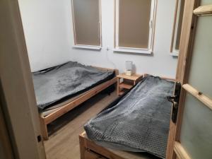 twee bedden in een kamer met twee ramen bij Leśna Chata kuracyjna z sauną w Borach Tucholskich in Bielska Struga