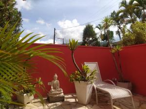 a patio with two chairs and plants in front of a red wall at Pousada Villa Encanto in Juquei