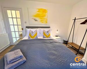 een slaapkamer met een bed met blauwe en gele kussens bij 1 Bedroom Apartment by Central Serviced Apartments - Close To University of Dundee - Sleeps 2 - Ground Level - Self Check In - Modern and Cosy - Fast WiFi - Heating 24-7 in Dundee