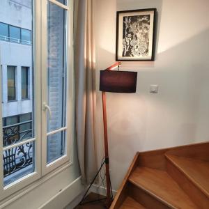 a room with a floor lamp next to a window at Charming & practical near Paris in Gentilly