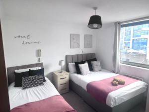 a bedroom with two beds and a window at Broad street - Balcony 1 bedroom apartment in Birmingham
