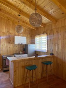 una cocina con 2 taburetes de barra en Cabañas Rumi Loft, en Valdivia