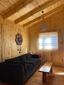 sala de estar con sofá negro y mesa en Cabañas Rumi Loft, en Valdivia