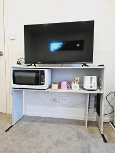 a microwave on a white stand with a tv on it at Hillcrest Home in Hamilton
