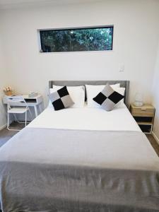 a bedroom with a large white bed with black and white pillows at Hillcrest Home in Hamilton