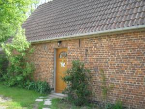 a brick house with a brown door and a yard at Gite "la Solitude" in Licques