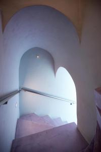 a stairway with an arch in a white wall at EDGE ON VOLCANO SUITES in Fira