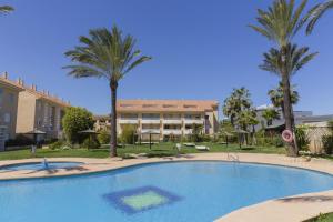 une piscine devant un immeuble avec des palmiers dans l'établissement Veranda Golden Beach II Apartment Javea Arenal, à Jávea