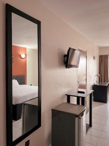 a mirror in a hotel room with a bed and a table at Résidences Les Hauts de l'Indenié in Abidjan