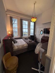 a bedroom with a bed and a chair and windows at The Office Bar and Restaurant in Dudley