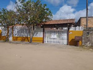 a white and yellow fence next to a building at pousada residencial santos in Nova Viçosa