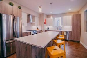 a kitchen with a large white counter and yellow stools at Denver Urban Retreat - 3BR Rooftop w City Views in Denver