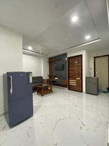 a kitchen with a refrigerator and a living room at Millennia service apartments in Hyderabad
