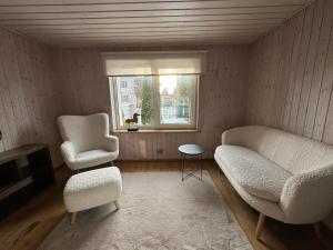a living room with a couch and two chairs and a window at Ristiku Guesthouse in Kuressaare