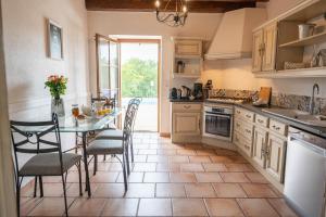 eine Küche mit einem Tisch und Stühlen sowie ein Esszimmer in der Unterkunft Villa en pierre 10 pers, piscine chauffée in Saint-Amand-de-Coly