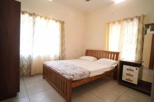 1 dormitorio con 1 cama y una ventana con cortinas en Joann Serviced Apartment en Thiruvalla