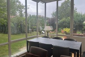 een kamer met een groot raam met een tafel en stoelen bij Villa and garden near Paris for the Olympic games in Garches