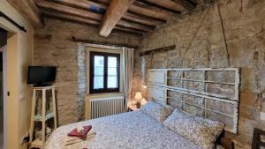 1 dormitorio con cama y pared de piedra en Bed and Breakfast Ballallaluna en Maiolo