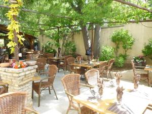 un patio al aire libre con mesas, sillas y árboles en Auberge de la Table Ronde, en Vinon-sur-Verdon