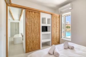 a bedroom with a bed and a tv and a window at Lil Paros Luxury suites in Dhragoulás