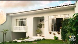 une maison blanche avec un balcon et des plantes dans l'établissement HOSTEL INN LAGO, à Guarapuava